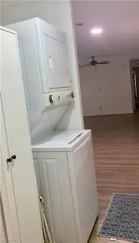 Washroom featuring light hardwood / wood-style flooring and stacked washing maching and dryer
