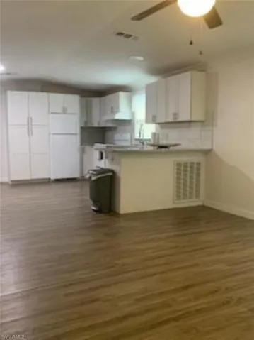 Kitchen featuring ceiling fan, white cabinets, white fridge, decorative backsplash, and dark hardwood / wood-style floors