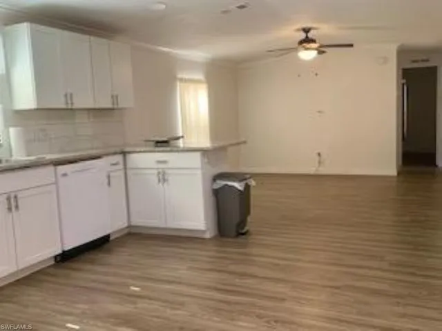 Kitchen featuring white dishwasher, white cabinets, light wood-type flooring, and ceiling fan