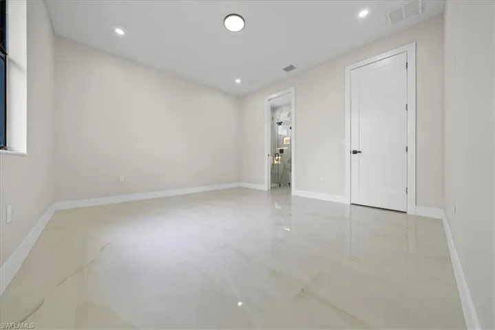 Polished tile flooring, recessed ceiling lighting, and a window with dark trim