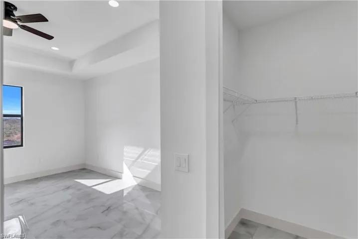 Spacious closet featuring marble look tile flooring and a ceiling fan