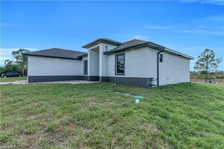 View of property exterior with stucco siding and a lawn