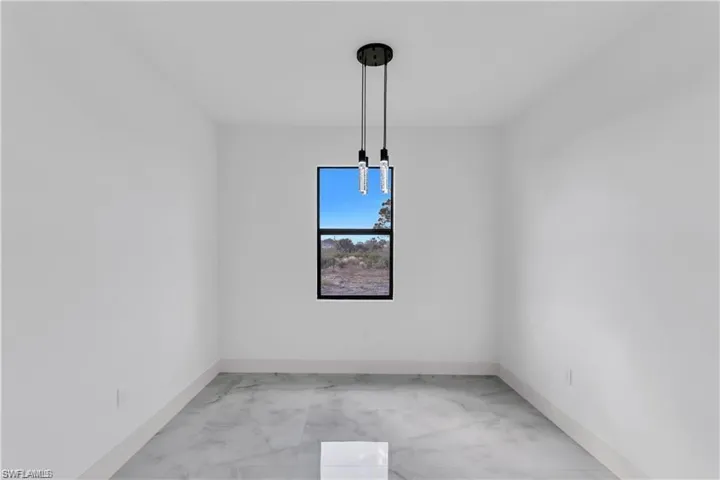 Empty room featuring light marble finish flooring and baseboards