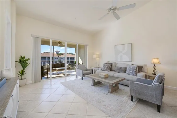 Living area with light tile patterned flooring, high vaulted ceiling, and ceiling fan