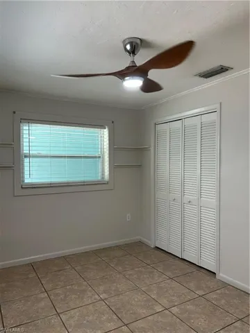 Unfurnished bedroom with visible vents, multiple windows, a closet, and ornamental molding