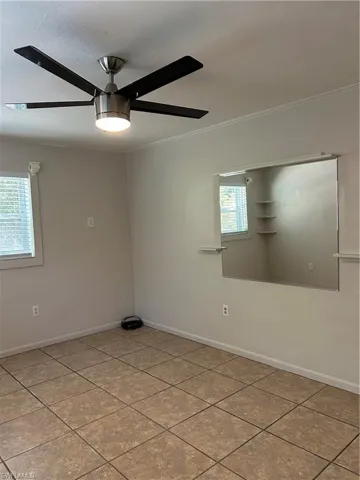 Spare room with tile patterned floors, baseboards, ornamental molding, and a ceiling fan