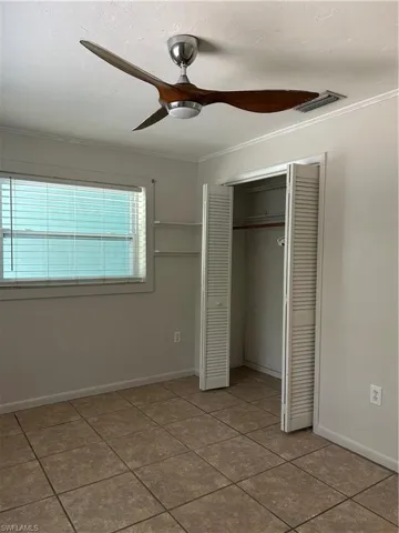 Unfurnished bedroom with a closet, visible vents, crown molding, and baseboards