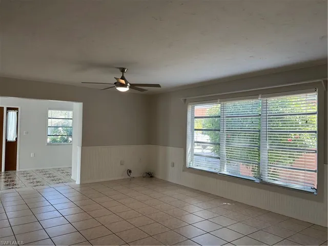 Unfurnished room featuring light tile patterned floors, a wainscoted wall, and a wealth of natural light