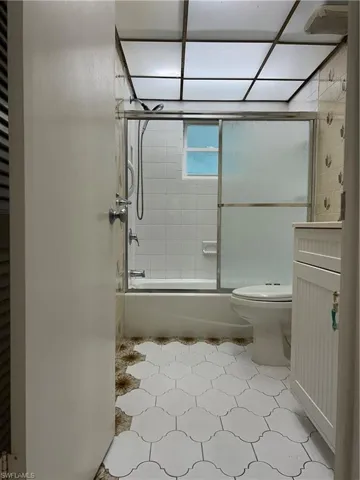 Full bath with combined bath / shower with glass door and toilet