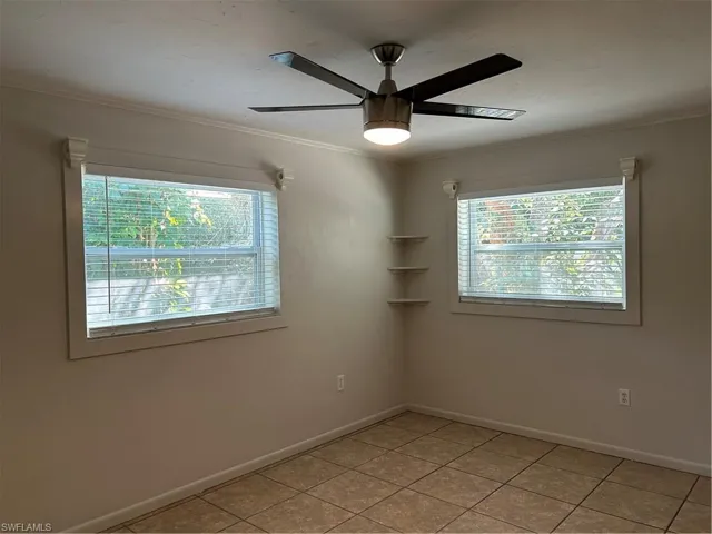 Unfurnished room featuring light tile patterned flooring, plenty of natural light, a ceiling fan, and ornamental molding