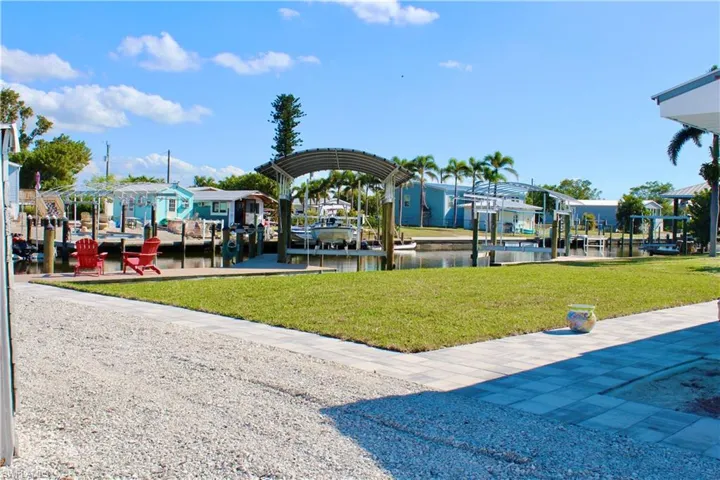 Dock area with boat lift, beautiful lawn, a water view, and a waterfront view
