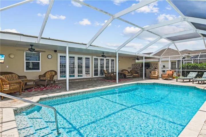 Outdoor pool with a ceiling fan, an outdoor hangout area, and glass enclosure