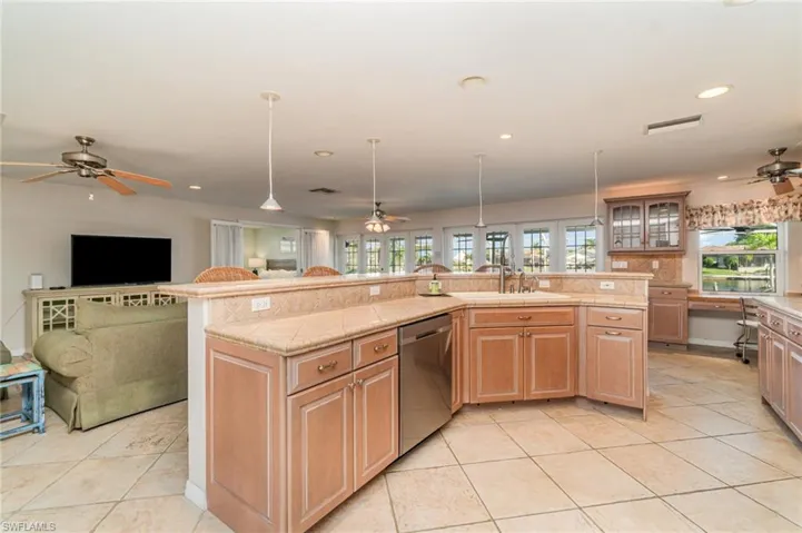 Kitchen with a ceiling fan, open floor plan, glass insert cabinets, light countertops, and recessed lighting