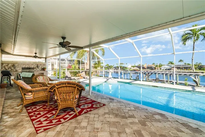 Outdoor pool with a ceiling fan, a water view, a lanai, a patio area, and a sunroom