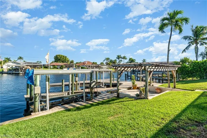 Dock area featuring boat lift, a yard, a water view, and a pergola