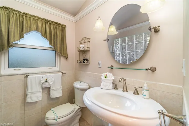 Bathroom featuring tile walls, wainscoting, and crown molding