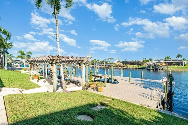 Dock featuring a yard, a water view, boat lift, and a pergola