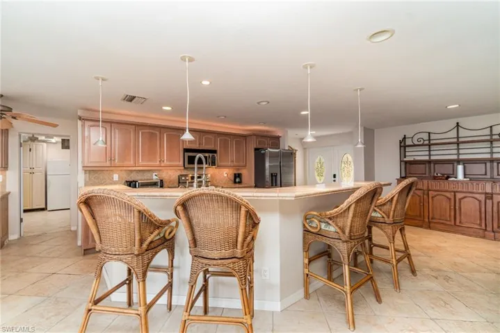 Kitchen with a kitchen breakfast bar, backsplash, pendant lighting, light countertops, and recessed lighting