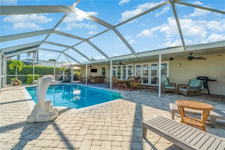 Outdoor pool featuring a ceiling fan, a sunroom, glass enclosure, a patio, and french doors