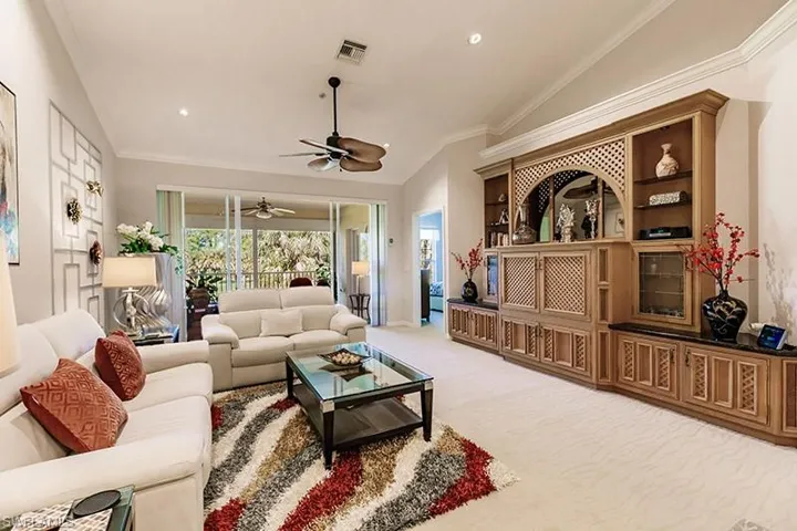 Carpeted living room with ornamental molding, ceiling fan, and vaulted ceiling