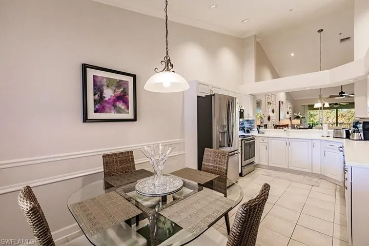 Tiled dining room featuring high vaulted ceiling, crown molding, and ceiling fan