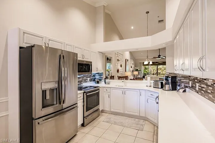 Kitchen featuring ceiling fan, tasteful backsplash, appliances with stainless steel finishes, and a high ceiling