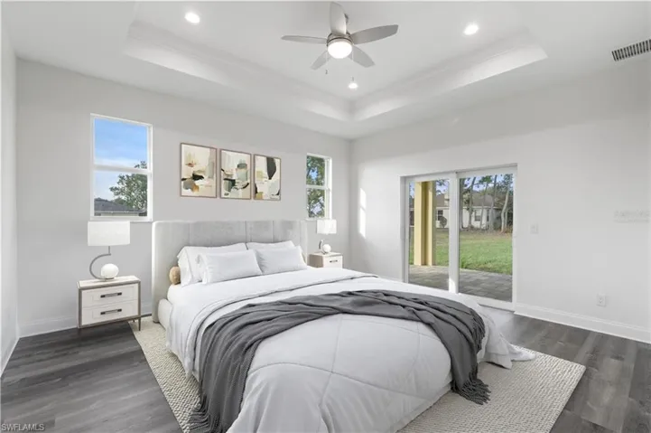 Bedroom with access to outside, a raised ceiling, recessed lighting, ornamental molding, and wood finished floors