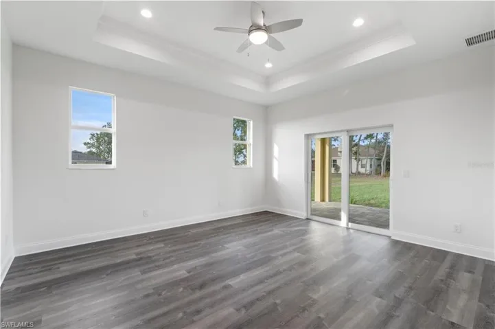 Spare room featuring a raised ceiling, ornamental molding, dark wood-type flooring, recessed lighting, and ceiling fan