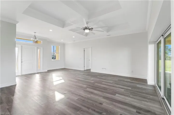 Unfurnished living room with coffered ceiling, recessed lighting, crown molding, dark wood-type flooring, and baseboards