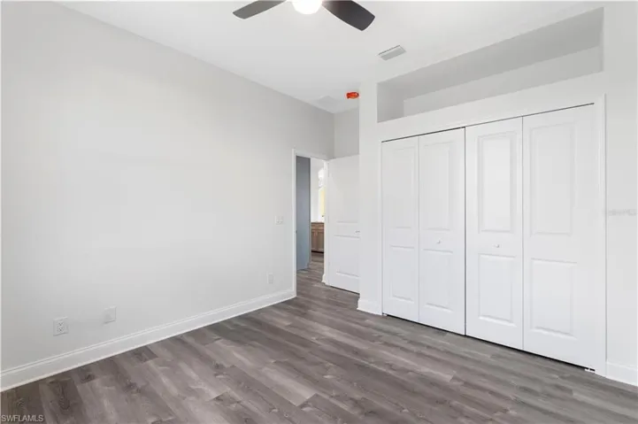 Unfurnished bedroom with wood finished floors, baseboards, a closet, and a ceiling fan