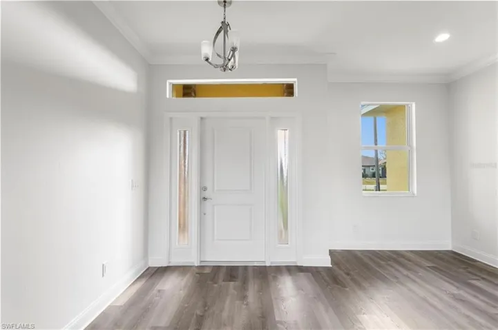 Entryway with ornamental molding, wood finished floors, baseboards, and recessed lighting