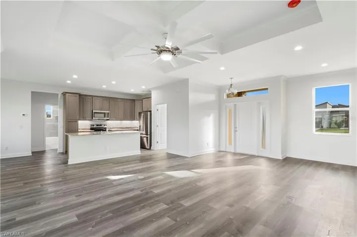 Unfurnished living room with coffered ceiling, a ceiling fan, ornamental molding, recessed lighting, and dark wood-type flooring