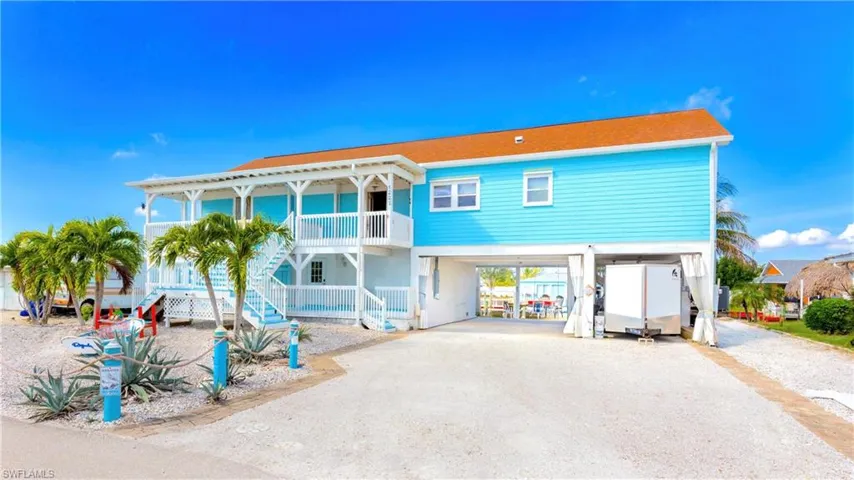 Back of house featuring a carport, driveway, stairs, and a balcony