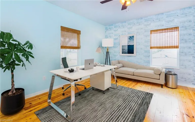 Office area with an accent wall, wallpapered walls, light wood-style floors, plenty of natural light, and ceiling fan