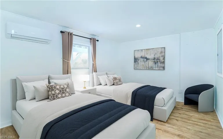 Bedroom with a wall mounted AC, wood finished floors, and recessed lighting