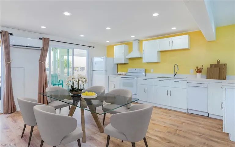 Kitchen featuring white cabinetry, recessed lighting, white appliances, wall chimney exhaust hood, and light wood-style floors