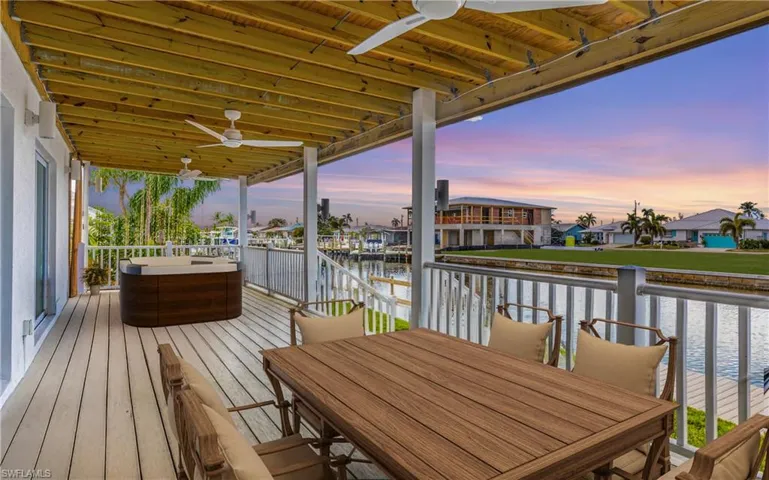 Wooden deck featuring ceiling fan, a water view, a residential view, and outdoor dining space