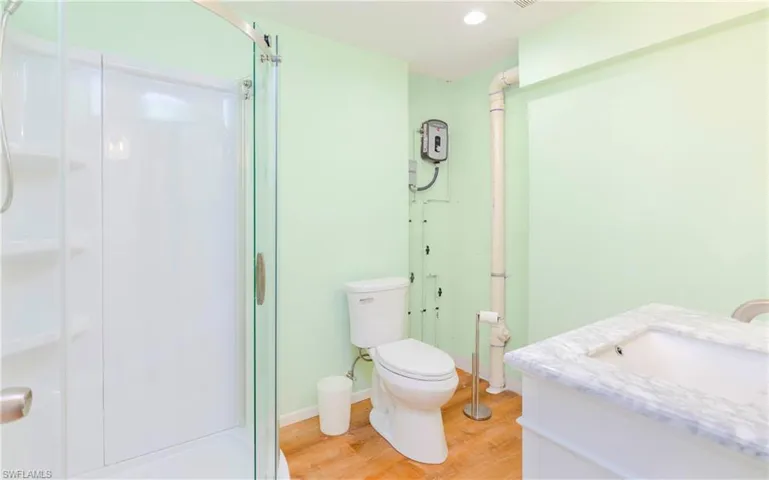 Bathroom featuring vanity, light wood finished floors, and a shower stall