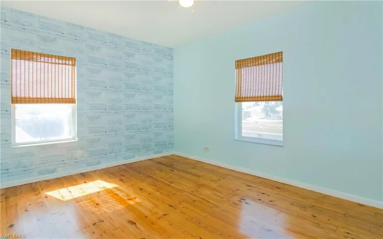 Spare room featuring wallpapered walls, wood-type flooring, and an accent wall