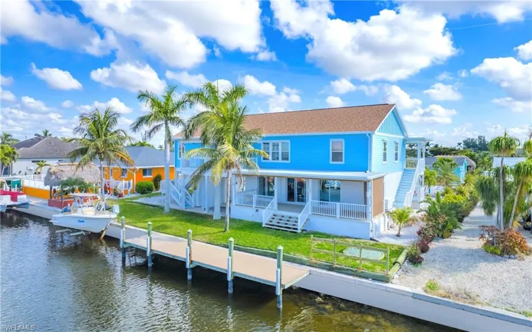 Rear view of house featuring stairs, a porch, and a water view