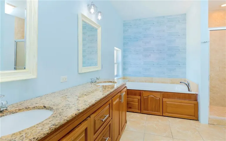 Full bathroom with a shower stall, a bath, double vanity, and light tile patterned flooring