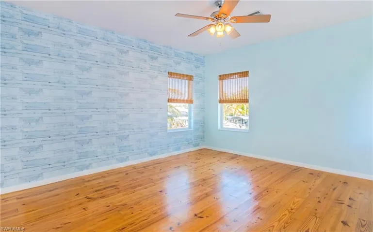 Unfurnished room featuring hardwood / wood-style floors, wallpapered walls, and a ceiling fan