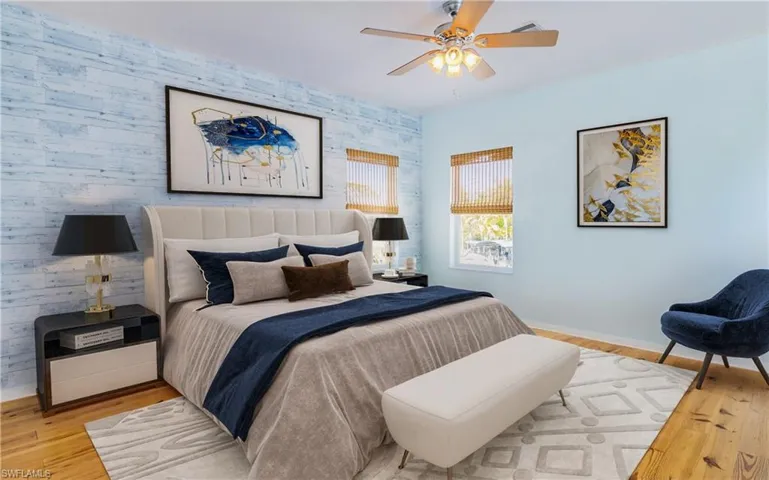 Bedroom with an accent wall, wood finished floors, ceiling fan, and wallpapered walls