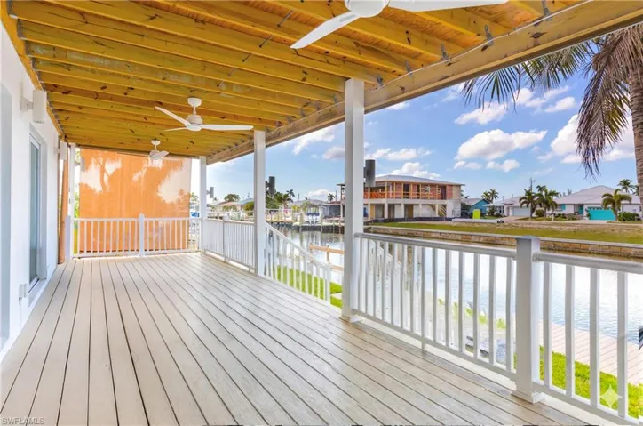 Deck with ceiling fan, a water view, and a residential view