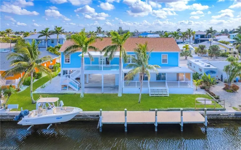 Rear view of house with a yard, a water view, a patio area, and boat lift