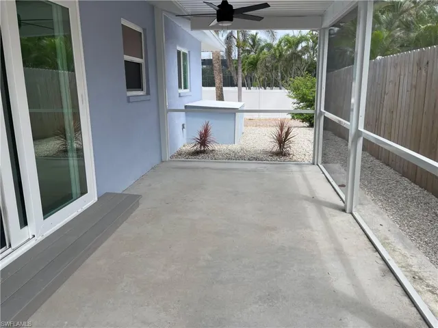 Screened patio with concrete flooring, modern ceiling fan, and composite step leading to sliding glass doors