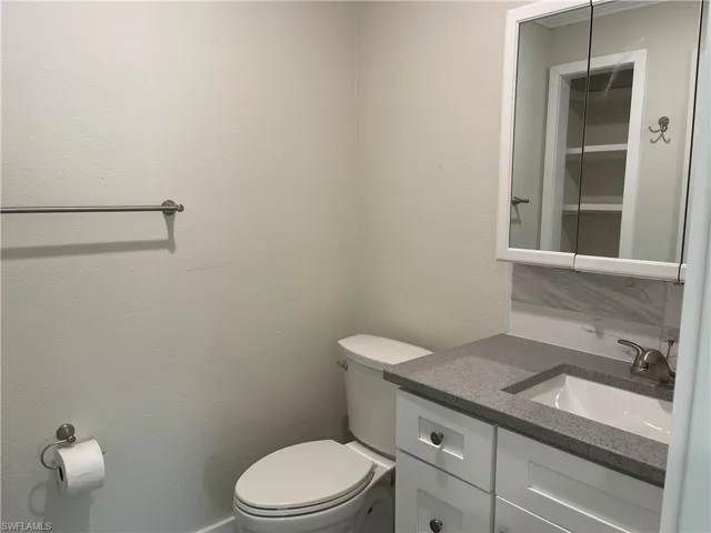 Bathroom vanity with a gray speckled countertop, white cabinetry, and brushed nickel hardware