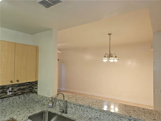 Kitchen featuring light stone counters, pendant lighting, and decorative backsplash