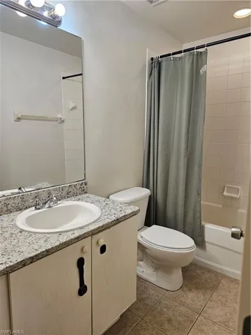 Full bathroom featuring vanity, light tile patterned flooring, and shower / bathtub combination with curtain