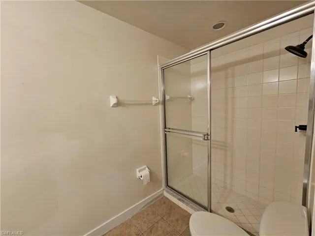 Full bath with a shower stall and light tile patterned floors
